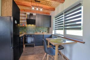 a kitchen with a table and a black refrigerator at Domki w Zielonym Gaju in Ustrzyki Dolne