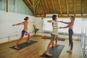 un grupo de tres jóvenes parados en una clase de yoga en Hotel Luna Llena, en Tamarindo