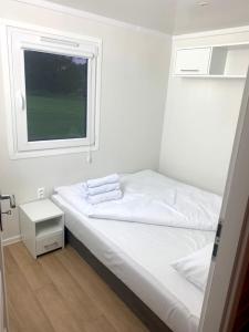 um quarto branco com uma cama e uma janela em Bungalow Camping Jacuzzi & Sauna em Solina