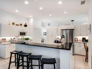 una cocina con armarios blancos y taburetes negros en Villa Champagne - 5322, en Siesta Key