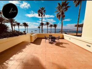 a balcony with a table and chairs and palm trees at Beach front Apartment in Taba