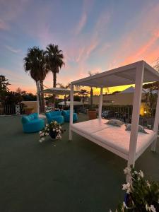 uma cama de dossel branca num pátio com palmeiras em Hotel Parco Delle Agavi em Ischia