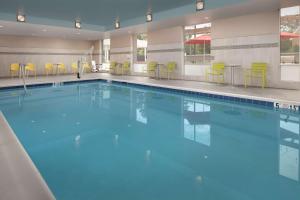 a large swimming pool with blue water and yellow chairs at Home2 Suites By Hilton Owings Mills, Md in Owings Mills