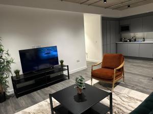 uma sala de estar com uma televisão, uma cadeira e uma mesa em Stylish Apartment in Greenwich em Abbey Wood