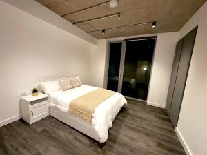 um quarto com uma cama branca e uma grande janela em Stylish Apartment in Greenwich em Abbey Wood