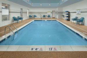 una gran piscina con sillas azules alrededor. en Home2 Suites By Hilton Charlottesville Downtown, en Charlottesville