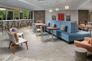 a lobby with a blue couch and tables and chairs at Home2 Suites By Hilton Charlottesville Downtown in Charlottesville