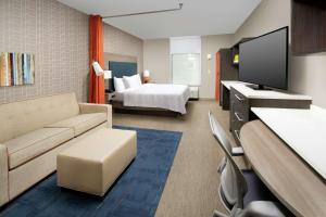 a hotel room with a couch and a bed at Home2 Suites By Hilton Charlottesville Downtown in Charlottesville