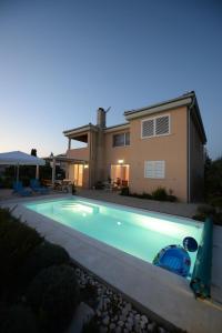a swimming pool in front of a house at Apartment Mara in Petrcane