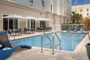 una piscina de hotel con sillas, mesas y sombrillas en Hampton Inn & Suites Lakeland-South Polk Parkway en Lakeland