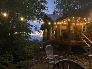 uma casa com luzes e uma cadeira em frente em Updated cabin nestled on 10 acres in the woods, breathtaking Blue Ridge Mountain views em Brevard