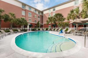 a swimming pool in a courtyard with chairs and a building at Homewood Suites by Hilton Orlando Airport in Orlando