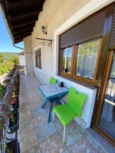 un patio con una mesa azul y sillas verdes en Apartman Lavanda, en Drvar