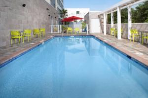 a large swimming pool with yellow chairs and tables at Home2 Suites By Hilton Miami Doral West Airport, Fl in Miami