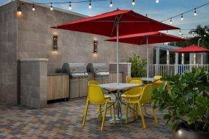 a patio with yellow chairs and a table with a red umbrella at Home2 Suites By Hilton Miami Doral West Airport, Fl in Miami