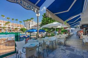 a patio with white tables and chairs and umbrellas at Cozy seaside apartment 215 in Parque Santiago 2 in Playa de las Americas +6 photos