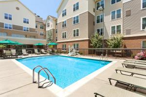 a swimming pool in a courtyard with chairs and a building at Homewood Suites by Hilton Reading-Wyomissing in Wyomissing