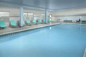 a large swimming pool with blue chairs and chairs at Tru By Hilton San Antonio Lackland Sea World in San Antonio