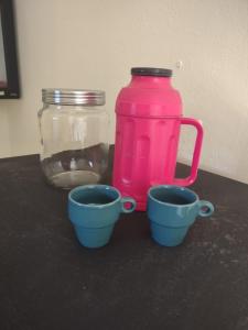 a pink pitcher and three cups on a table at Studio 2 próximo ao Centro in Palmas