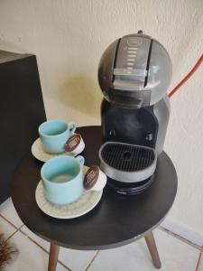 eine Kaffeemaschine und zwei Tassen auf dem Tisch in der Unterkunft Studio 2 próximo ao Centro in Palmas