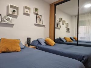 2 camas en una habitación con sábanas azules y almohadas amarillas en Acogedor piso cerca de la playa, en Puerto Sagunto