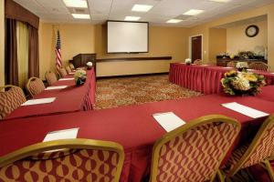 Hampton Inn and Suites San Antonio Airport في سان انطونيو: قاعة اجتماعات بها طاولات حمراء وكراسي وشاشة