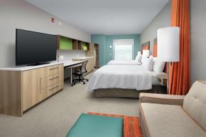 a hotel room with a bed and a desk with a television at Home2 Suites By Hilton Asheville Biltmore Village in Asheville