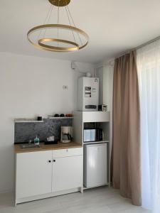 una cocina con armarios blancos y una lámpara de araña en Stefan Studio, en Năvodari