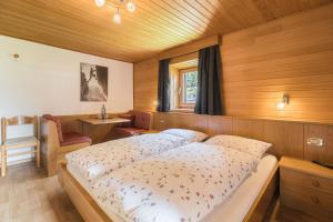 a bedroom with two beds and a chair in it at B&B Ciauceia in Selva di Val Gardena