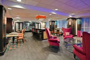 a waiting room with red chairs and a table at Hampton Inn Ithaca in Ithaca