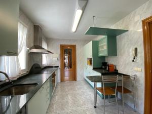a kitchen with green cabinets and a table in it at Casa Ideal Grupos y familias a 5 minutos de Pamplona, jardín particular y txoko in Barañáin