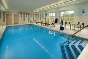 a large swimming pool with blue water and chairs at Hampton Inn & Suites Syracuse/Carrier Circle in East Syracuse