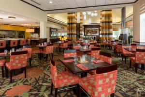 um restaurante com mesas e cadeiras e um bar em Hilton Garden Inn Buffalo Airport em Cheektowaga