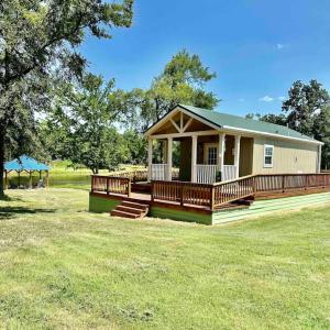 uma pequena casa com um grande deque num campo em Small Home near Lake Fork with Stocked Pond em Emory