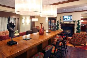 a large table in a lobby with chairs and a fireplace at Hampton Inn Springfield South Enfield in Enfield