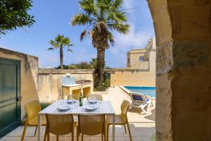 a table and chairs on a patio next to a pool at Dar tas-Soru Farmhouse with Private Pool in Għasri