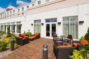 une terrasse avec des chaises et des tables en face d'un hôtel dans l'établissement Hilton Garden Inn Wayne, à Wayne