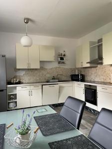 a kitchen with white cabinets and a table with chairs at Ferienhaus Weise in Alt Töplitz