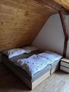 Cama en habitación con techo de madera en Chalupa Olšinka, en Velké Poříčí