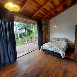 a bedroom with a bed and a large window at Chalé dos Altos de Laranjeiras in Paraty