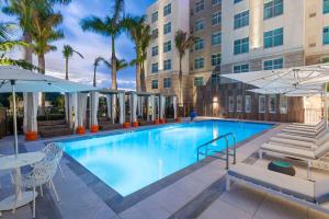 a swimming pool at a hotel with tables and umbrellas at Homewood Suites by Hilton Sarasota-Lakewood Ranch in Sarasota