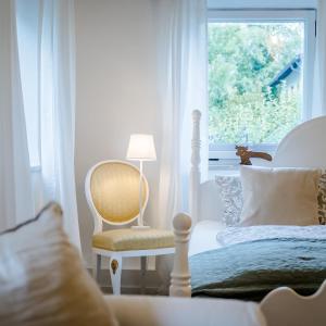 een slaapkamer met een bed, een stoel en een raam bij Seenswert - Vegane Pension und Ferienwohnungen am Ammersee in Pähl