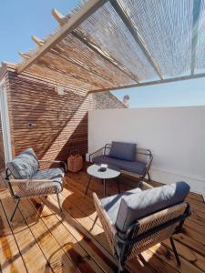 een patio met stoelen en een tafel op een houten vloer bij LE MAJORELLE in Marseillan