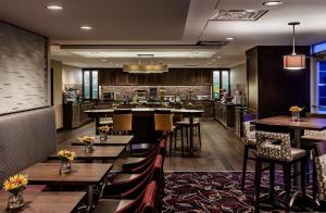 a restaurant with tables and chairs and a bar at Homewood Suites by Hilton Buffalo/Airport in Cheektowaga