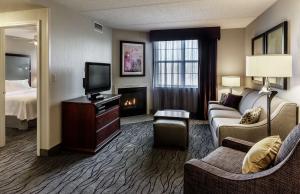 Habitación de hotel con sofá, TV y chimenea. en Homewood Suites by Hilton Buffalo/Airport, en Cheektowaga