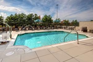 Hilton Franklin Cool Springs في فرانكلين: حمام سباحة في الفندق مع الكراسي والطاولات
