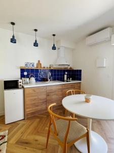 a kitchen with a white table and chairs and a counter at LE MAJORELLE in Marseillan