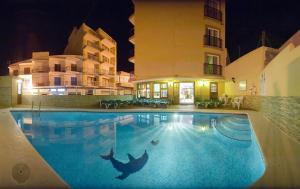 a swimming pool in front of a building at night at Hostal Adelino in San Antonio