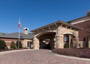a brick building with a flag in front of it at Homewood Suites Denton in Denton