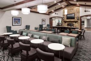 a waiting room with tables and chairs and a fireplace at Homewood Suites Denton in Denton